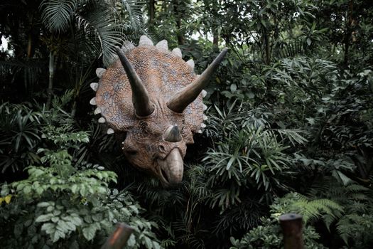 Illustratie van verschillende dinosaurussen in een prehistorisch landschap met T. rex, Triceratops en Brachiosaurus